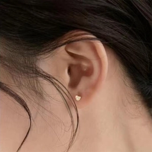 Close-up of minimalist heart stud earring in gold finish worn on the earlobe