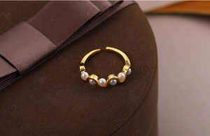 Macro view of wave-shaped 18k gold pearl ring featuring five round white pearls