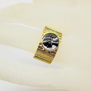 Macro view of vintage gold-tone ribbed band ring with an ancient portrait emblem