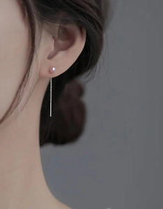 Détail macro de boucles d'oreilles pendantes en argent avec perle rose sur modèle