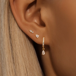 Macro shot of 925 silver gold-plated teardrop earrings and zircon studs for a layered look