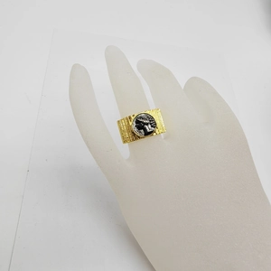 Detailed view of vintage rectangular gold ring with coin portrait on a display hand