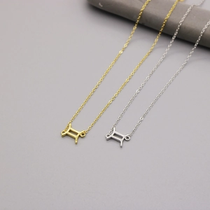 Close-up of Gemini constellation pendants in polished gold and silver on fine chains