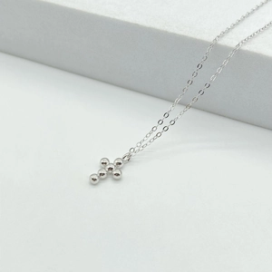 Close-up of a minimalist 925 sterling silver necklace featuring a cross bead pendant