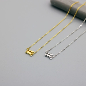 Detail of silver and gold zodiac necklaces with wave Aquarius pendants on stone