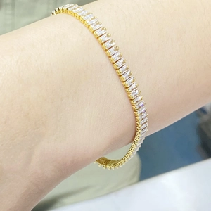 Dettaglio di un bracciale tennis dorato con zirconi rettangolari con taglio a baguette
