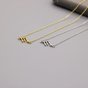 Detailed view of Scorpio zodiac pendants in polished gold and silver on minimalist chains