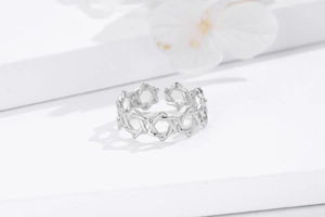 Macro detail of silver open ring with hollow star pattern on a white display