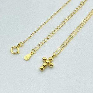 Macro detail of 925 sterling silver S925 stamp on a gold cross bead necklace