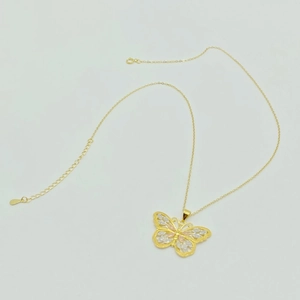 Détail du pendentif papillon tricolore avec filigrane complexe sur une chaîne en argent