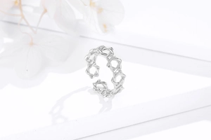 Macro detail of adjustable 925 silver hollow star ring on elegant white textured surface