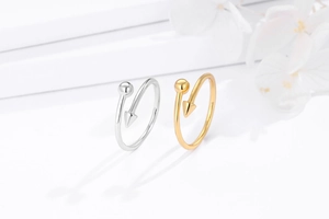 Detail of gold and silver wrap rings featuring ball and arrow tips on white pedestal