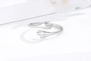 Detailed view of polished S925 silver embrace ring with hands hugging design
