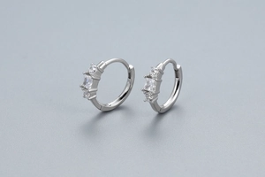 Macro shot of silver hoop earrings featuring three claw-set clear zircon stones