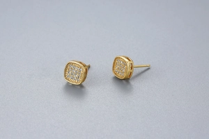 Macro view of square S925 silver stud earrings with pavé zircons and gold plating