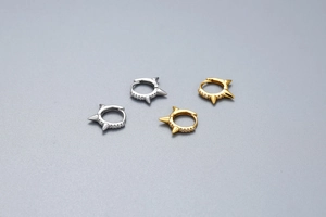 Macro shot of silver and gold spiked huggie earrings with micro-pave cubic zirconia