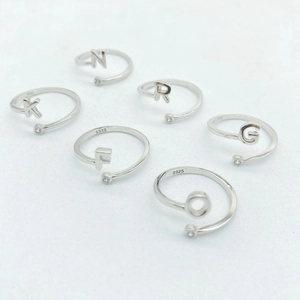 Close-up of S925 sterling silver open rings featuring gold letters and zircon accents