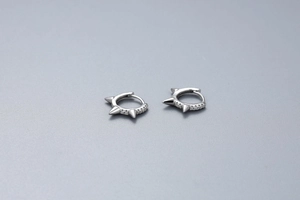 Close-up of punk style S925 silver hoop earrings with rivet spikes and pavé zircons