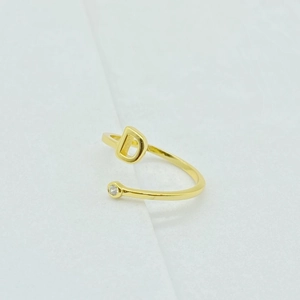 Detail of adjustable gold ring with sparkling cubic zirconia and capital letter D