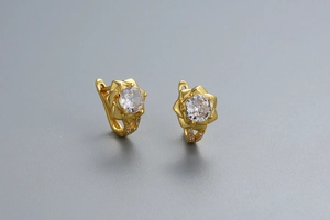 Gros plan sur des boucles d'oreilles fleurs dorées avec zircons et fermoir levier