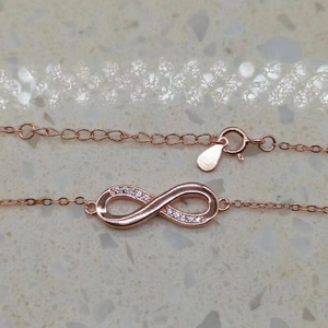 Close-up of rose gold infinity bracelet featuring pave-set cubic zirconia and lobster clasp
