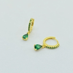 Close-up of gold hoop earrings with pear-cut green stone and sparkling gemstones