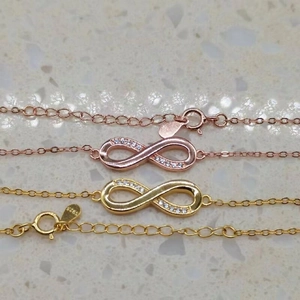Detail of S925 sterling silver infinity bracelets with cubic zirconia in gold and rose gold
