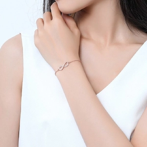 Rose gold infinity bracelet with sparkling cubic zirconia on female model's wrist