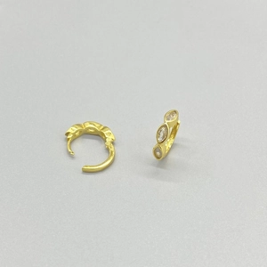 Détail de boucles d'oreilles créoles dorées avec trois zircons clairs de taille marquise