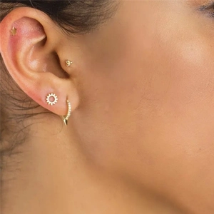 Macro shot of gold punk earrings set featuring star, sun motifs and spiked hoop with zircons