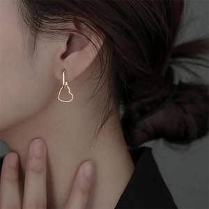 Close-up of 18K gold heart-shaped earrings with zircon accents on model