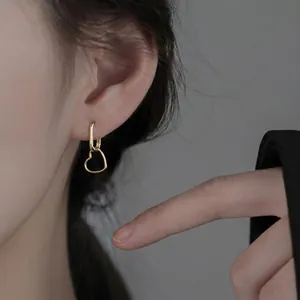 Minimalist 925 sterling silver heart hoop earrings with elegant gold finish on model