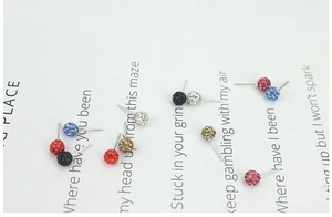 Macro detail of multicolor disco ball crystal stud earrings set on decorative white card