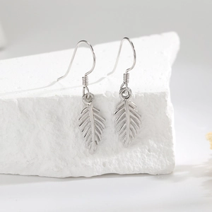 Elegant 925 sterling silver leaf drop earrings hanging on a white textured stone