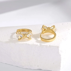 Minimalist S925 sterling silver bow earrings with zircon stones on a white stone base