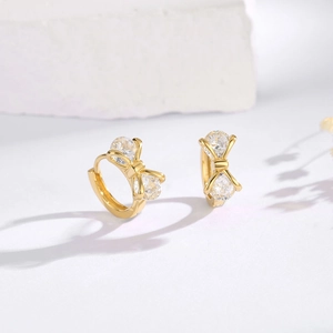 Close-up of golden bow earrings with sparkling round cubic zirconia in a prong setting