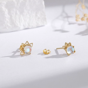 Macro detail of asymmetric lotus stud earrings with moonstone on white background