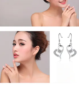 Détail de boucles d'oreilles cœur en argent massif S999 avec zircons sur un mannequin