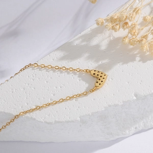 Detail der 14K vergoldeten Herzkette mit hohler Rückseite auf elegantem weißem Stein