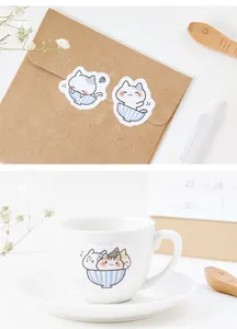 Close-up of cute cartoon cat stickers decorating an envelope and a white coffee mug
