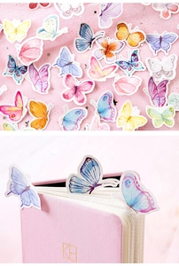 Macro view of watercolor butterfly stickers on pink mesh and leather journal