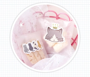 Detailed view of cat stickers on semi-transparent gift bags with cozy grid pattern