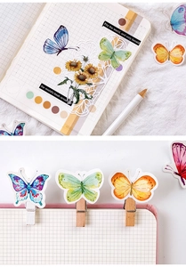 Macro detail of watercolor butterfly stickers and mini wooden clips for scrapbooking