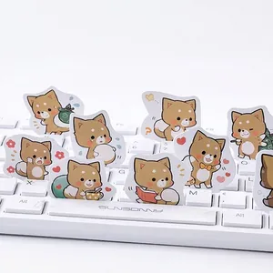 Simpatici adesivi Shiba Inu per diari, mostrati su una tastiera meccanica bianca di design