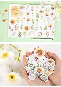 Detail of sunflower and daisy stickers on grid paper with hand showing scale