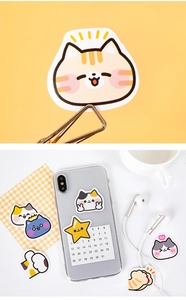 Close-up of cat-themed DIY stickers on a phone case and yellow background scene