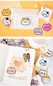 Close-up of decorative cat stickers on a journal page with grid paper and boxed packaging