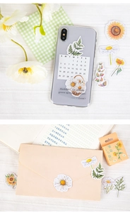 Daisy and sunflower stickers decorating a phone case and envelope in a vintage style