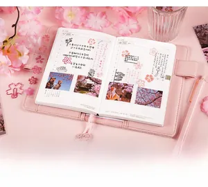 Detailed close-up of cherry blossom themed stationery kit with pink leather notebook cover