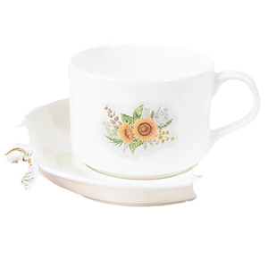 Ceramic tea cup and saucer set featuring sunflower and wildflower stickers on white background